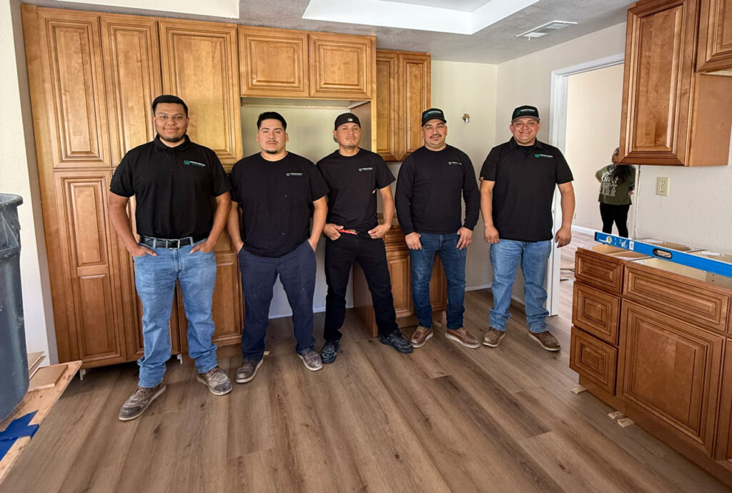 A team of five remodeling professionals standing together in a newly installed kitchen, showcasing their expertise and teamwork.